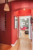 Red fitted cupboards in hallway with red walls and view into bedroom