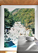 Stacked plates and glasses on counter in front of large landscape photo