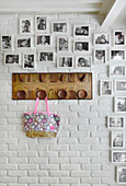 Framed black and white family photos and coat rack on white-painted brick wall