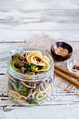 Noodles with beef and broccoli in a glass jar