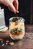 Salad with white cabbage, carrots, green salad, fennel, orange and walnuts in a jar, vegan