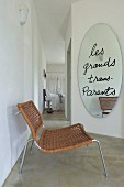 Loungestuhl vor ovalem Wandspiegel mit Spruch und Blick in Schlafbereich