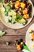 Vegan tacos with sweet potatoes, corn, black beans and avocado on a wood background.