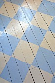 White wooden floor painted with pale blue chequered pattern