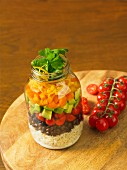 A Santa Fe bowl with rice, beans, cherry tomatoes, avocado and cheese in a glass jar (Mexico)