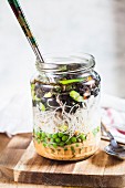 Vegane DIY-Instantsuppe Thai-Style mit Erdnuss-Chili-Paste, Erbsen, Glasnudeln, Frühlingszwiebeln und Rosenkohl, mit Wasser aufgegossen