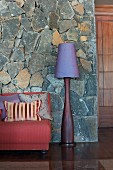 Sofa and standard lamp against stone-clad wall