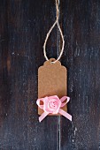 Brown paper tag with pink fabric rose and ribbon