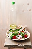 Veganer Salat (Einkorn, Tomaten, Feldsalat, Zwiebelringe, Eisbergsalat, Kresse, Pfeffer) auf einem Palmenblattteller