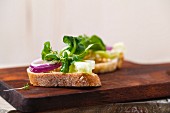 Baguettescheibe mit Olivenöl und Salat (Feldsalat, Kresse, Zwiebeln, Eisbergsalat, Einkorn)