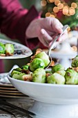 Hand serving brussels sprouts with spoon