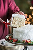 Hands serving slice of coconut cake