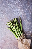 A bunch of fresh asparagus spears in a paper bag tied with string
