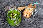 Green cabbage soup in a glass jar with pomegranate seeds and feta cubes