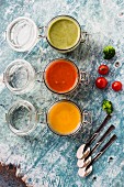 Various colourful soups in glass jars (broccoli soup, tomato soup, pumpkin soup)