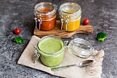 Various colourful soups in glass jars (broccoli soup, tomato soup, pumpkin soup))