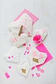Transparente Origamiherzen mit Konfetti auf pinkem Papier