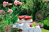 Raspberry cake on a cake stand in a summer garden