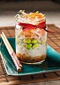 Edamame bean salad in a trendy lunch jar with chopsticks on a teal plate and bamboo mat