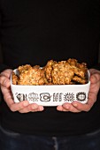 A man's hands holding a dish of oat biscuits