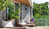 Sofa and floor cushions on terrace with glass balustrade