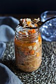 Pasta soup with prosciutto and vegetables in a glass jar