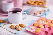 French Madeleines on a white wooden table with blue and pink decorations and a cup of coffee