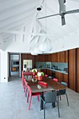 Black and red chairs around dining table in open-plan kitchen