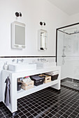 Twin sinks on washstand and shower cubicle in black and white bathroom