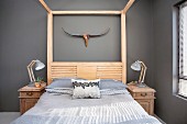 Wood-framed bed and bedside cabinets against grey wall