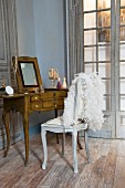 Antique dressing table and white feather boa on chair