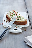 A slice of bread with chive cream and pink peppercorns