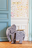 Old wooden elephant toy in front of wainscoting