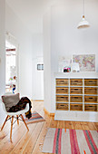 Classic chair in front of open doorway and tall chest of drawers in period apartment