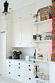 Ample storage and vintage ornaments in bright country-house kitchen