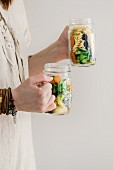 A woman in a linen dress holding two salad jars