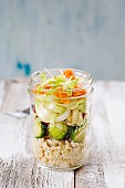 Salad in a glass with couscous, brussels sprouts, apple, chicory, carrot and lentil sprouts