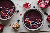 A smoothie bowl with pomegranate seeds, blueberries and granola