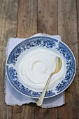 Natural yoghurt on a white and blue saucer with a teaspoon
