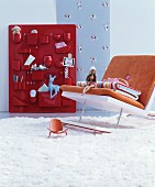 Modern rocking chair in front of toys in red organiser on wall
