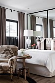 Elegant bedroom in earthy shades with cream bed against mirrored wall