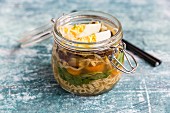 Ramen soup with spinach, bamboo shoots, carrots, egg and mushrooms in a glass jar