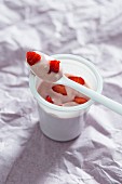 Soya yoghurt in a plastic pot with fresh strawberries (vegan)