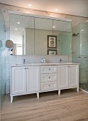 White washstand below mirrored cabinet on marble wall