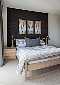 Double bed below framed pictures on black structured wall in bedroom