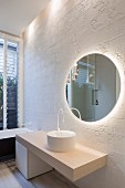 Round mirror on white structured wall tiles in minimalist bathroom