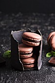 Chocolate french macarons with ganache filling on a black table