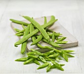 Green beans, some chopped, on a chopping board
