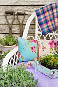 White wicker chair with cushions and fabric-covered tray filled with potted fresh herbs in garden