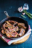 Pork ribs in a pan with garlic and fresh herbs